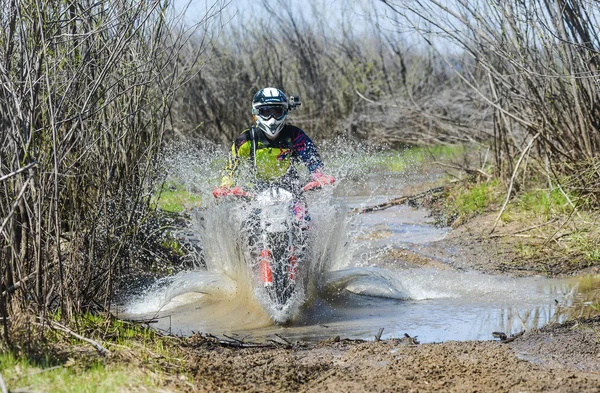 Enduro motorcycle rides through the mud with a big splash