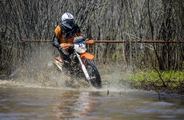 Enduro motorcycle rides through the mud with a big splash