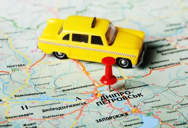 Map with red pin and a taxi toy