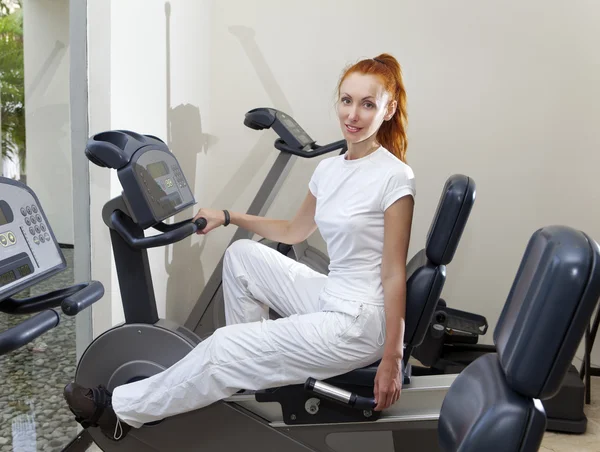 Young sports woman in sport center on velosimulator