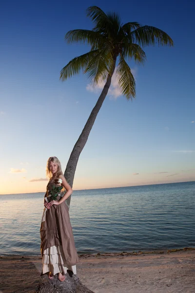 The young woman in a long sundress on a tropical beach. Polynesia.