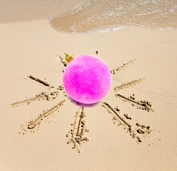 New Year's ball in the center of the sun drawn on sand on a beach