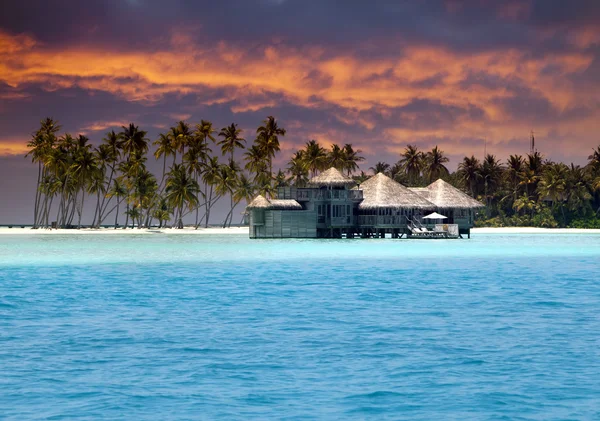 Island in ocean, overwater villas at the time sunset