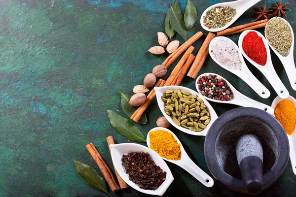 Various herbs and spices for cooking on old green background,