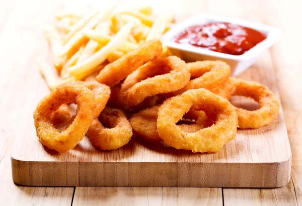 Onion rings and fried potato with ketchup