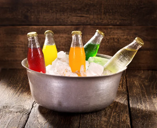 Various bottles of soda in the bucket with ice