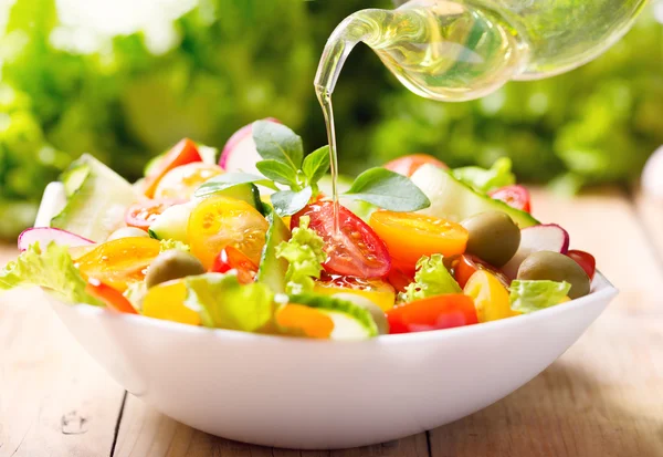 Olive oil pouring over vegetable salad