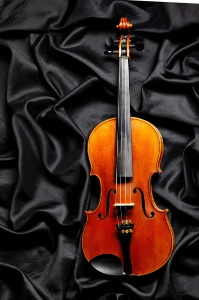 Aged violin on dark fabric texture