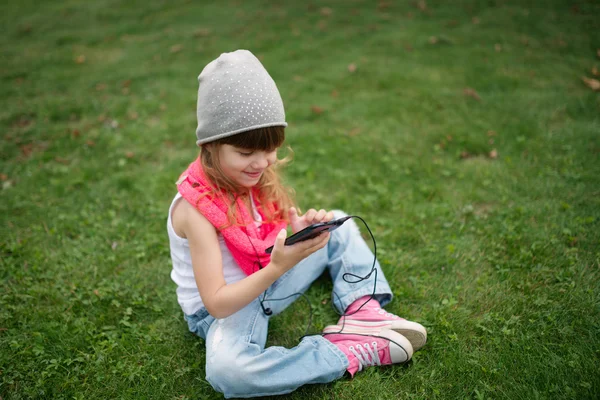 Little girl with mobile phone on the grass