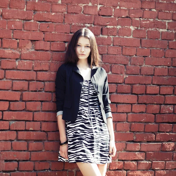 Beautiful girl near red brick wall