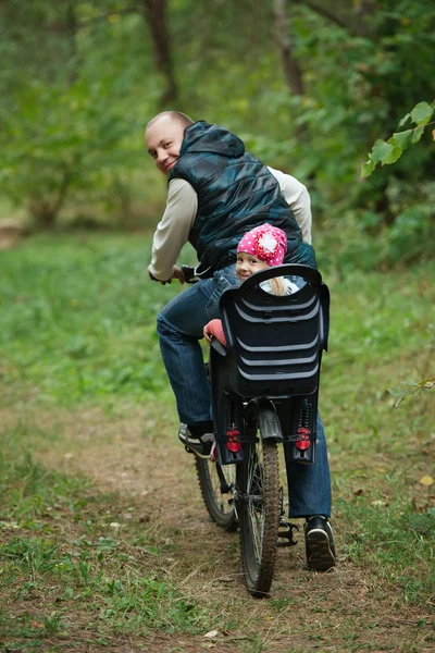 Father and daughter riding bike in the forest