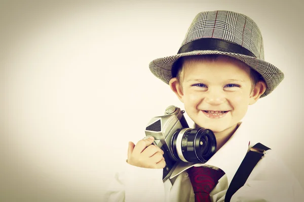 Young boy playing with an old camera to be photographer