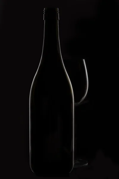Wine glass and bottle on black background rim lighting