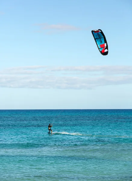 Unknown kitesurfer surfing on a flat azure water of Atlantic ocean in Corralejo, Fuerteventura, Canary islands, Spain