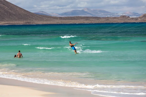 Unknown kitesurfer surfing on a flat azure water of Atlantic ocean in Corralejo, Fuerteventura, Canary islands, Spain