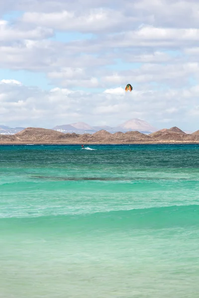 Unknown kitesurfer surfing on a flat azure water of Atlantic ocean in Corralejo, Fuerteventura, Canary islands, Spain