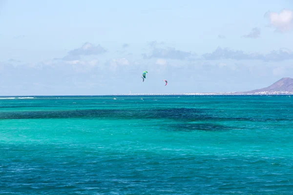 Kitesurfers surfing on a flat azure water of Atlantic ocean in Corralejo. Fuertevetnura, Spain
