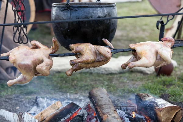 Whole chicken being roasted on an open fire