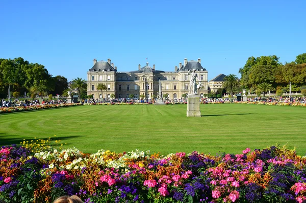 People enjoy sunny day in the Luxembourg Garden in Paris. Luxembourg Palace is the official residence of  the French Senate.