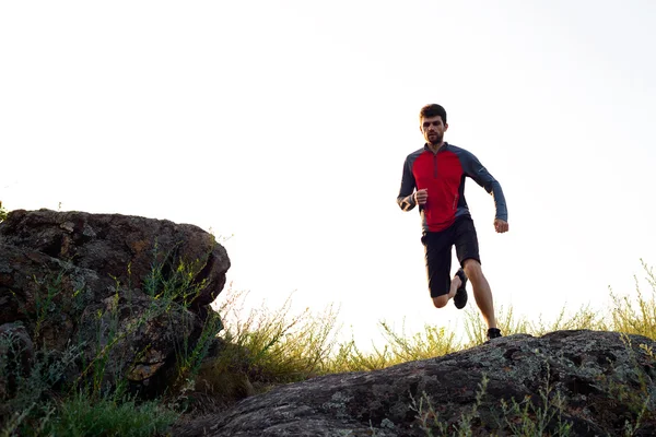 Young Sportsman Running on the Rocky Mountain Trai in the Evening. Active Lifestyle