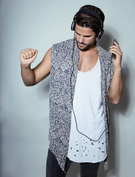 Handsome young fit man in sleeveless shirt listening to music