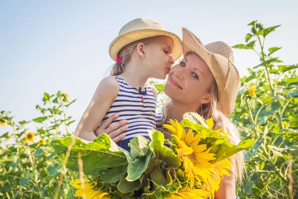 Mother and daughter kissing among sunflower field