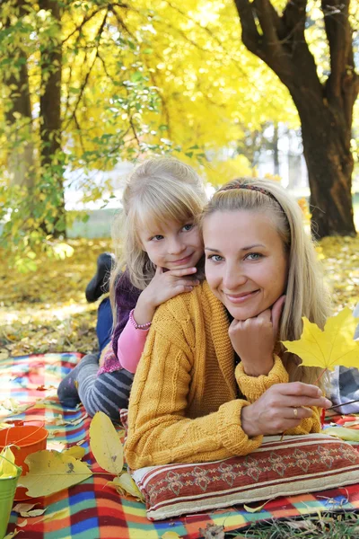 Mother and daughter lying under autumn tree