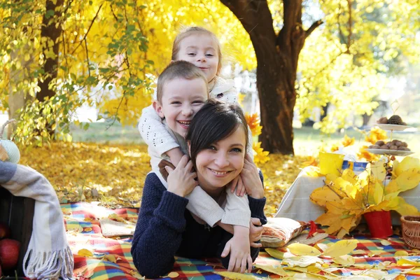 Happy children hugging mother under autumn trees