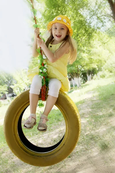 Girl in yellow dress on tire swing