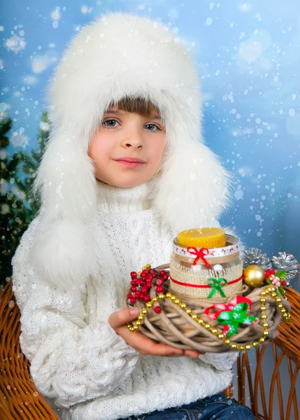 Beautiful girl in a white cap and knit sweater holding a candle