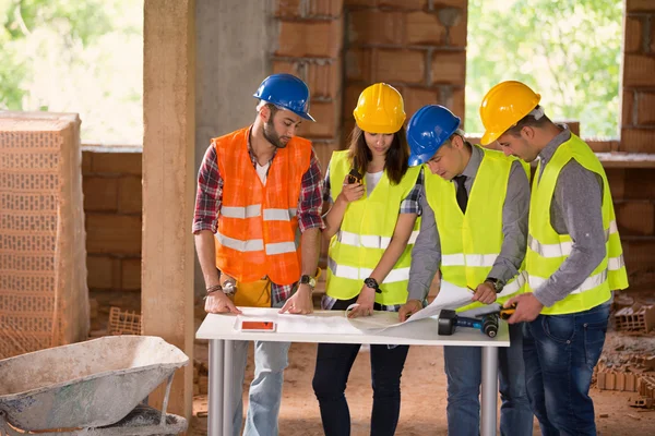 Engineers at construction site studying blue print
