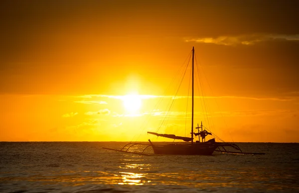 Fishing boat silhouette in ocean over evening sunlight