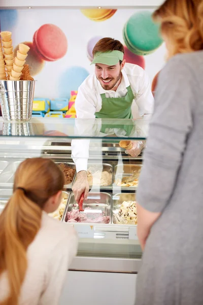 Worker in pastry store serving girl with ice cream