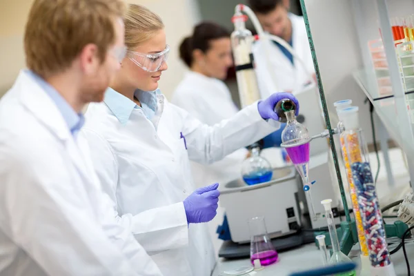 Female chemical technician mixing fluids in laboratory