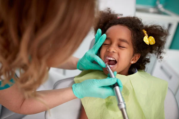 Female dentist patiently polish teeth to child