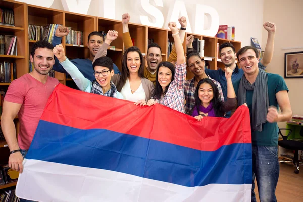 Group of students hold Serbian flag and raised victory fists