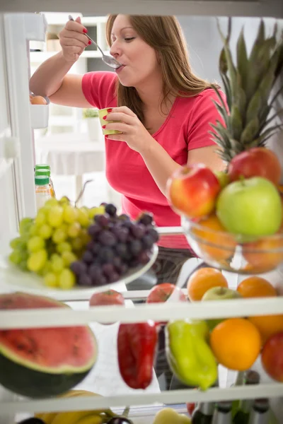 Female eat fruit yogurt from fridge