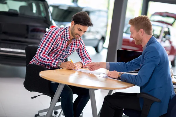 Car dealer explaining sales contract to man buying a car