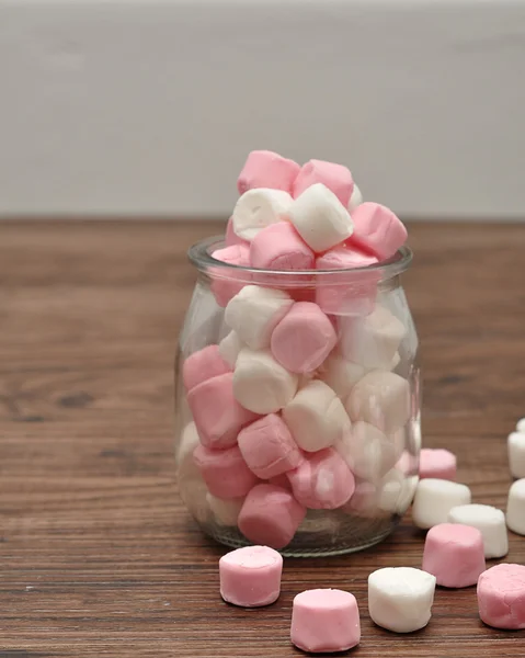 A bottle filled with small pink and white marshmallows