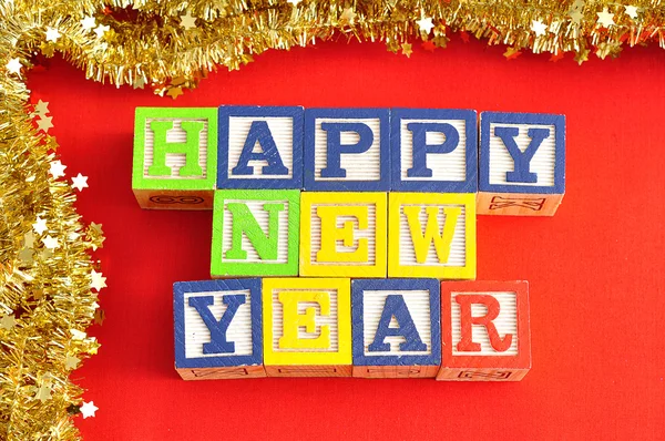 Happy new year spelled with alphabet blocks and golden tinsel