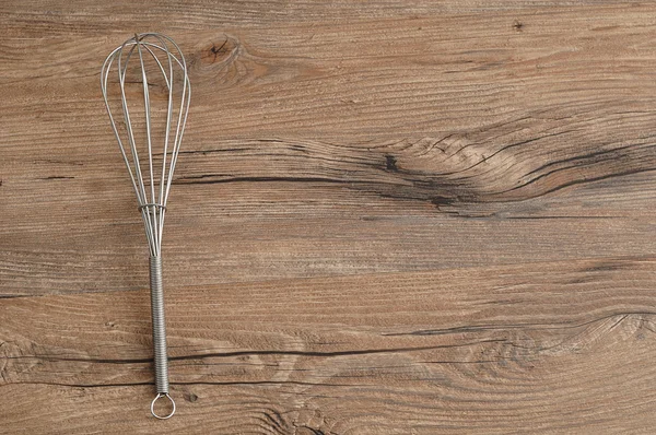 Egg beater, whisk, isolated on a wooden background