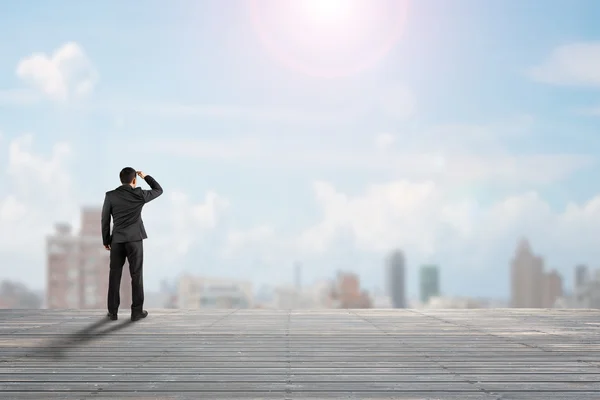 Businessman rear view gazing at city on old wooden floor