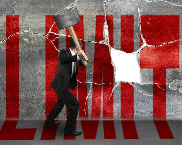 Businessman destructing the wall with a large hammer