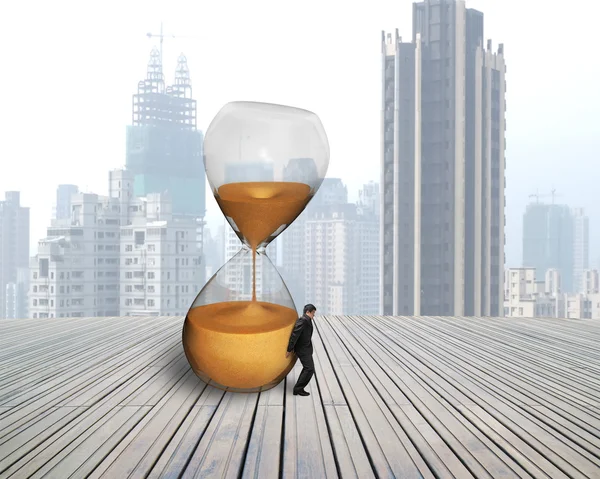 Businessman hold the inclined hourglass