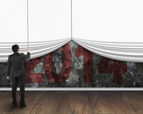 Businessman pulling down white blank curtain to cover old 2014