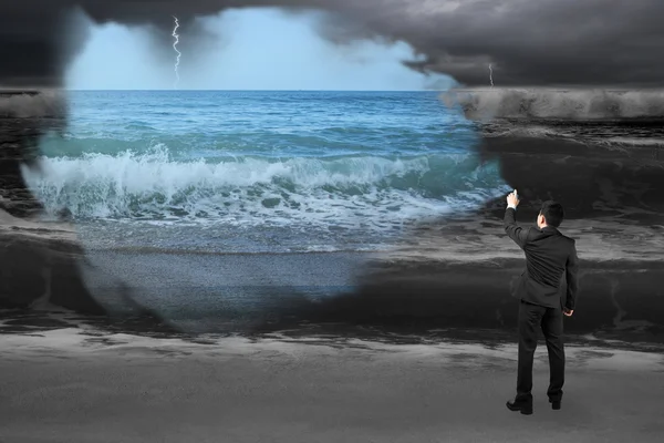 Businessman spraying calm sea paint covered dark stormy ocean