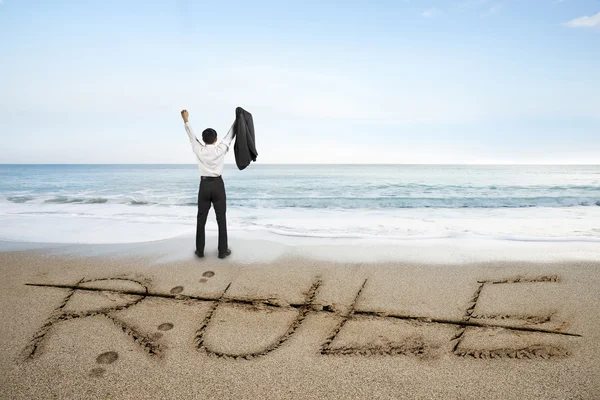 Businessman cheering with rule word deleted line on sand beach