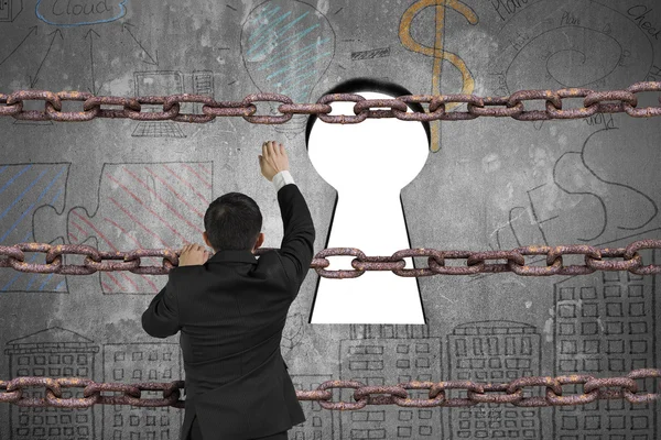 Businessman climbing on iron chain for keyhole with blank white