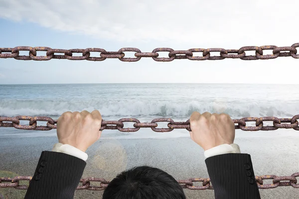 Businessman climbing on iron chains with natural sky sea