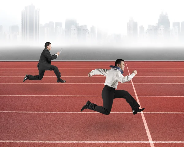 Two businessmen running on red track